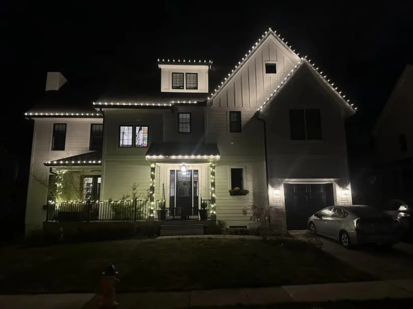 Christmas light installation in the DMV — warm white roofline and porch accents on a custom home