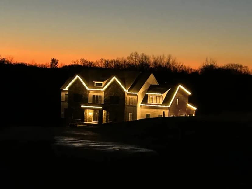 Christmas light installation in the DMV — warm white roofline at dusk on a custom home