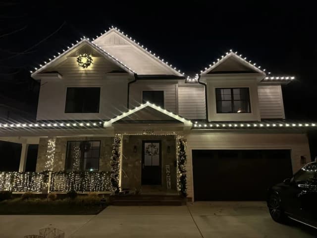 Christmas light installation in the DMV — bright warm white roofline at night