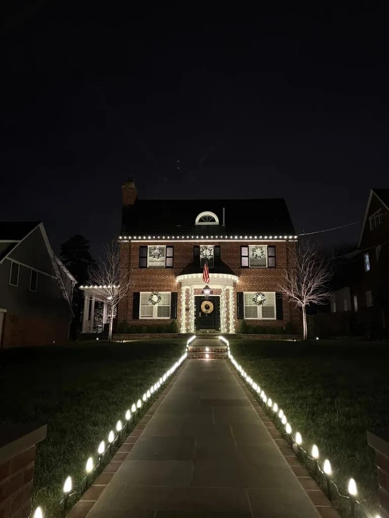 Christmas light installation in the DMV — warm white accents on a brick home with lit pathway