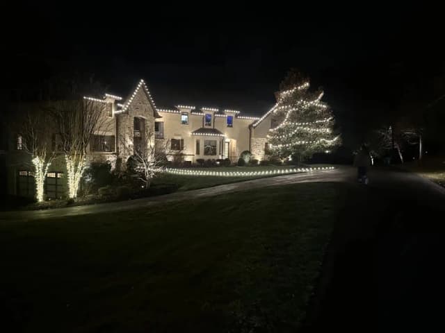 Christmas light installation in the DMV — broad warm white roofline on a large home
