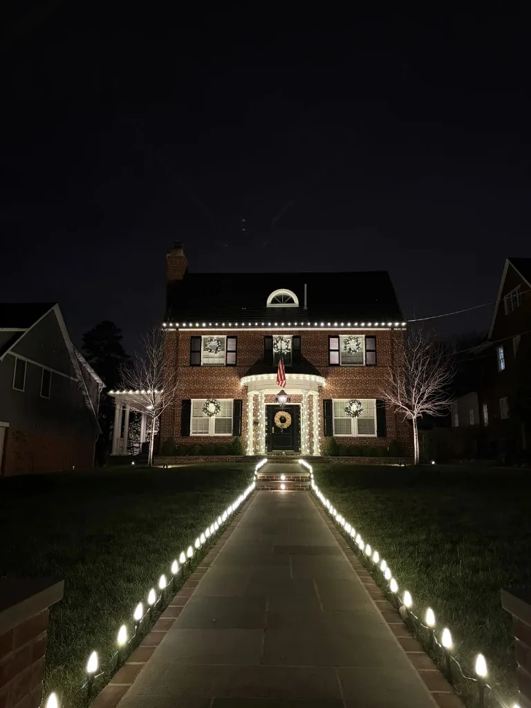 Christmas light installation in the DMV — warm white accents on a brick home with lit pathway